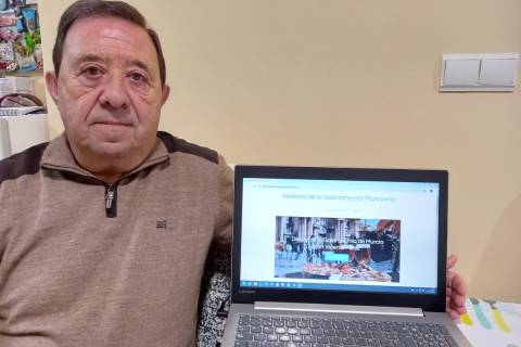 Vicente Pérez junto a un portátil con la web que ha creado.